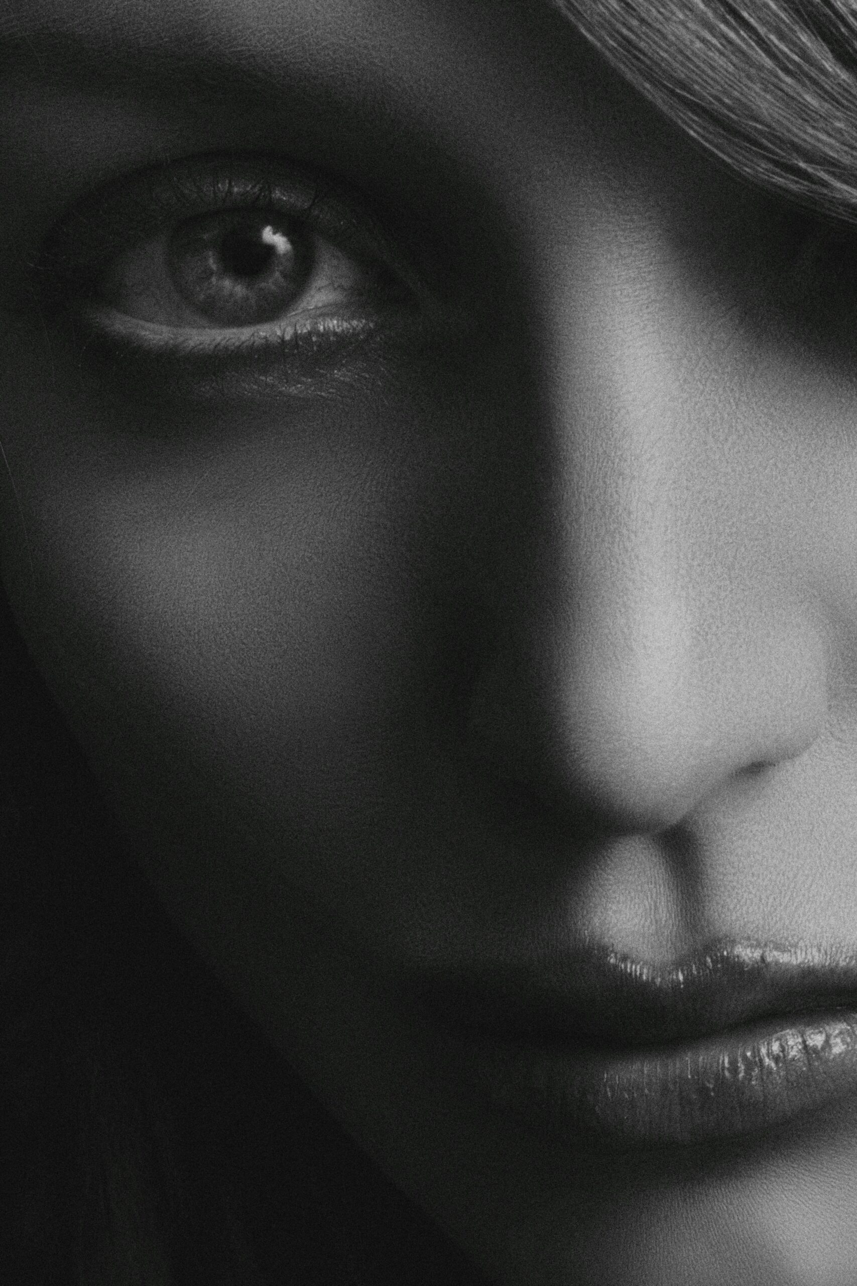 Artistic black and white close-up portrait of a woman's face focusing on her eye and lips.